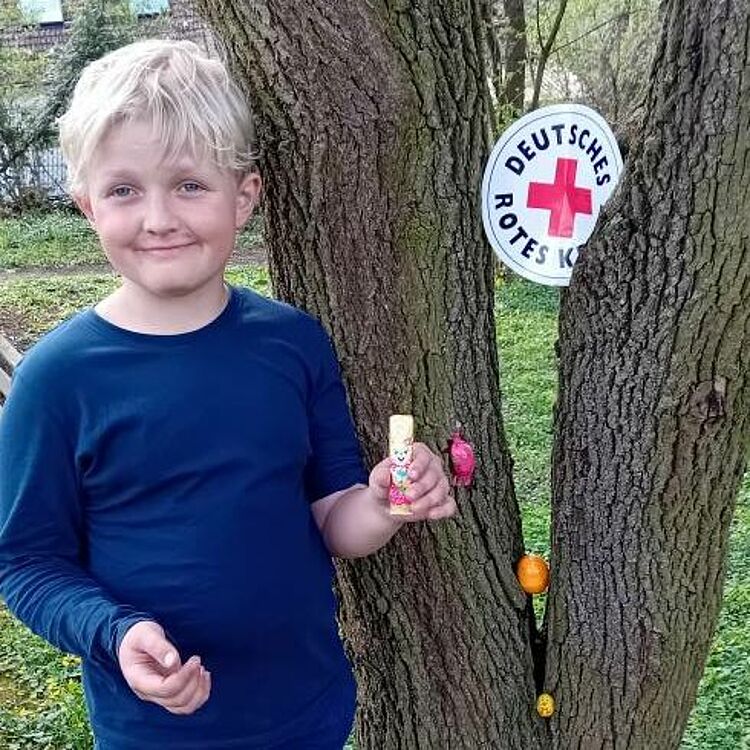 Junge hat bei der Suche erfolgreich Ostereier und Süßigkeiten gefunden, welche er stolz präsentiert.